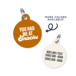 A rust colored dog ID Tag with white text stating a funny quote: you had me at snacks