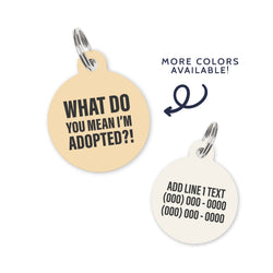 A light yellow colored dog ID Tag with dark grey text stating a funny quote: what do you mean i'm adopted?!