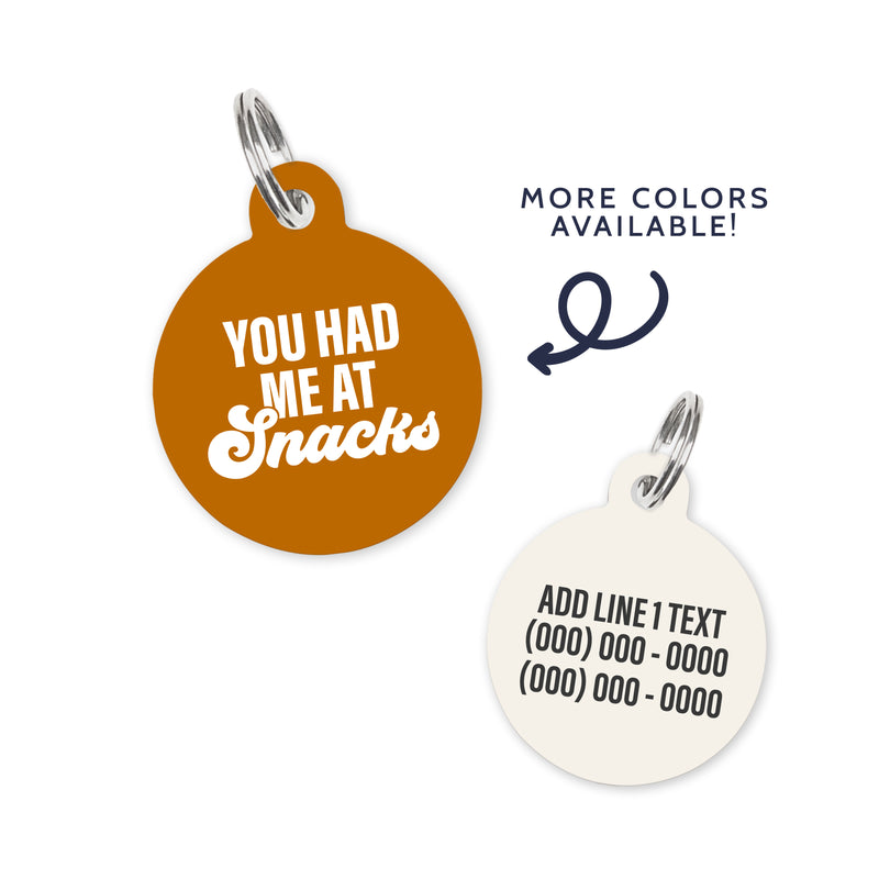 A rust colored dog ID Tag with white text stating a funny quote: you had me at snacks