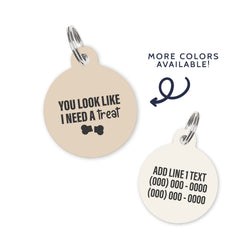 A beige colored dog ID Tag with dark grey text stating a funny quote: you look like i need a treat
